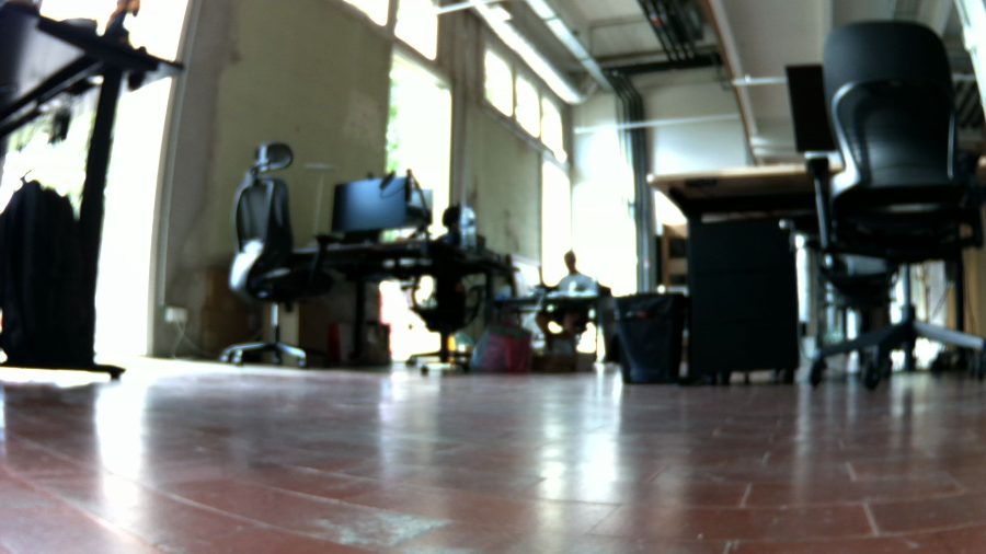 A blurry robot camera frame of the office showing the soft lens